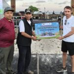 Pimpinan Saraya Resort, Adrian James Campbell, (kanan) menyerahkan Flayer pembangunan Arena hiburan anak Pengantap kepada Kepala Desa Induk Buwun Mas, Rochidi, S.IP., (dua dari kiri). (Foto perspectivesnews/Bil)
