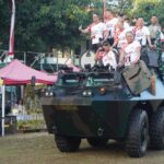 Gubernur Bali Wayan Koster, didampingi Pangdam IX/Udayana, Danrem 163/Wira Satya, Danlanud I Gusti Ngurah Rai serta Danlanal Denpasar bersama beberapa pelari lainnya larut dalam kecerian bersama, sambil naik tank keliling Lapangan Makorem 163/Wira Satya, usai mengikuti "PRIMA Fun Run", Minggu (20/9/2026). (Foto: djo)